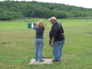 Instructor observing a student shooting a shotgun