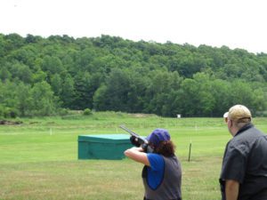 Woman in a vest shooting a gun at a far distance