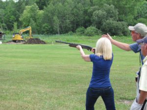 Woman in blue learning how to shoot a shotgun