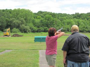 Woman in pink shooting a gun at an angle