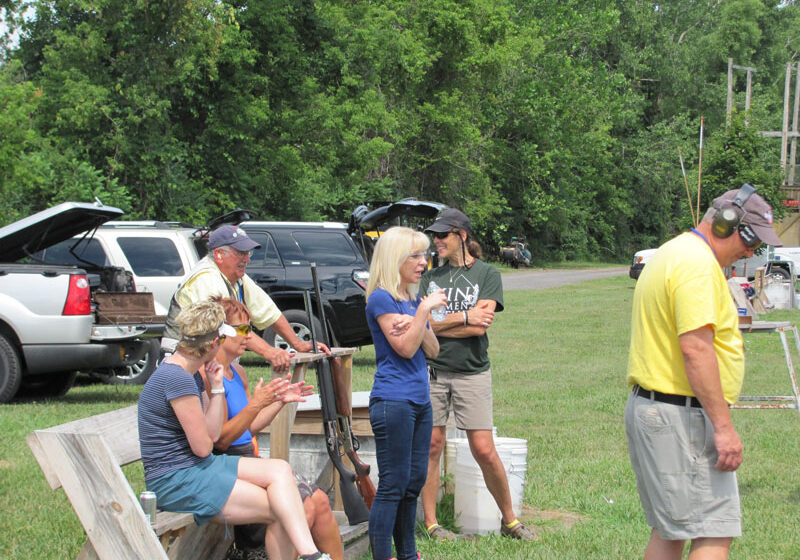 Woman in blue with a group of shooting sports enthusiasts